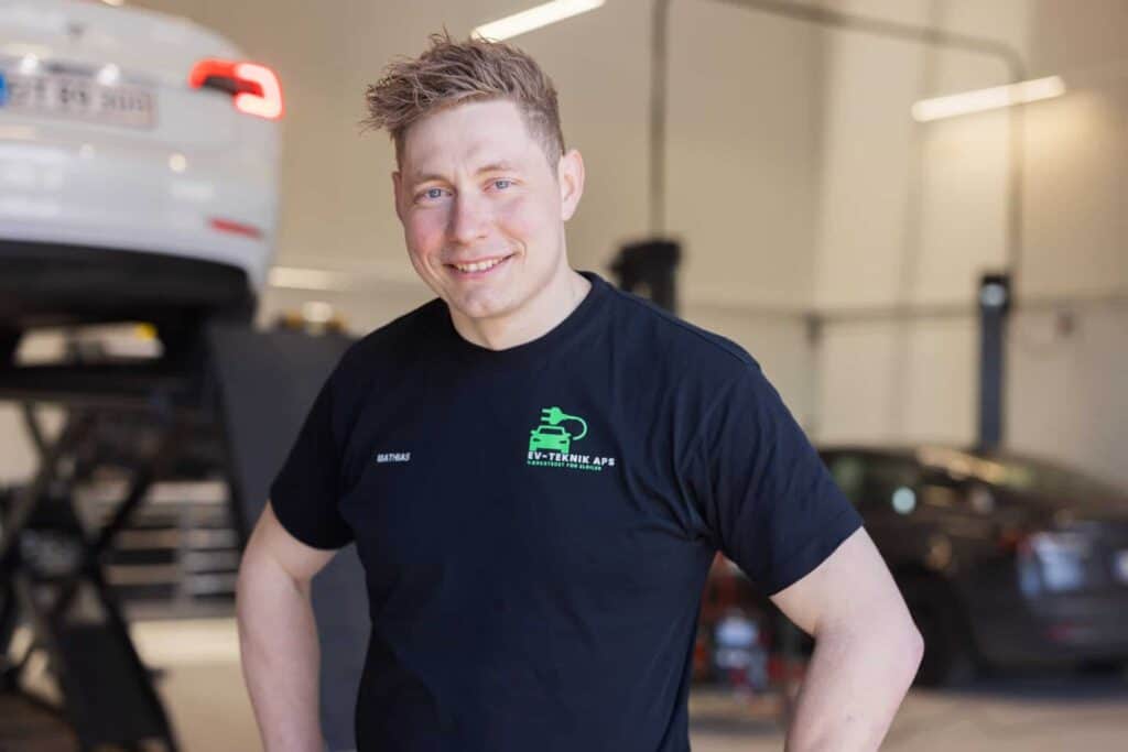Smilende elbil-mekaniker i sort t-shirt hos EV Teknik