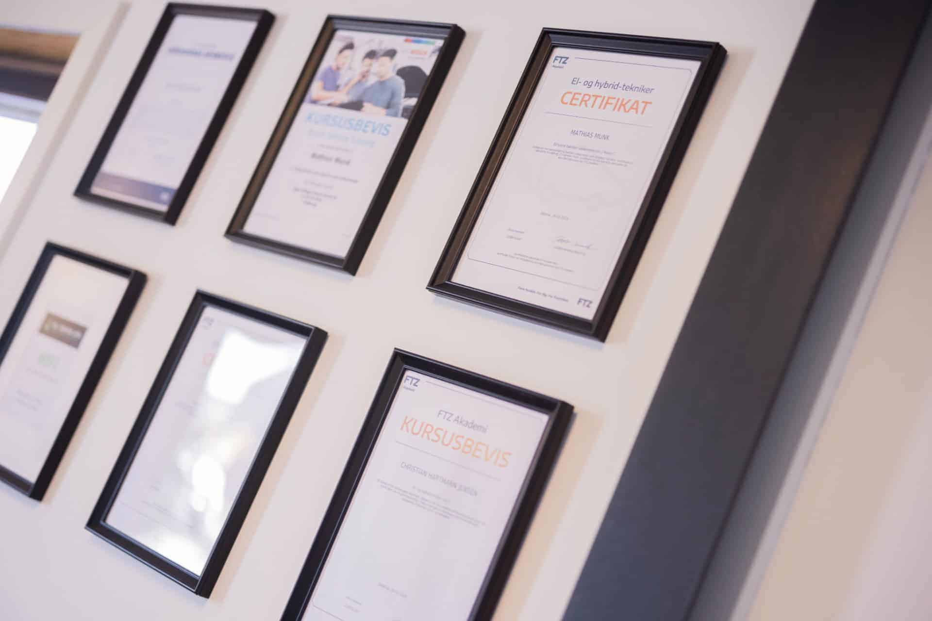 Indrammede certifikater og diplomer på væggen hos EV Teknik